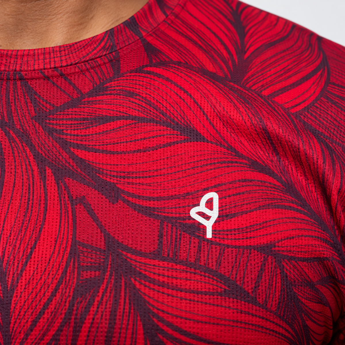 YUL Crimson Red men's running shirt, red and black, close-up of the chest emblem.