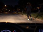 Runner seen from a car at night, with reflective heel panels illuminated by the headlights.